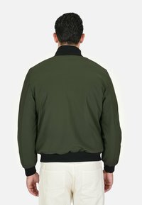 Giacca bomber verde oliva con colletto e polsini neri. Texture liscia, vita elasticizzata e design imbottito, vista da dietro.