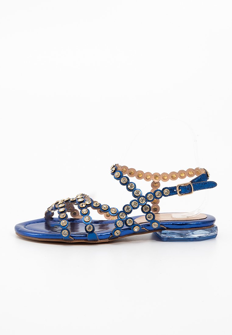 Infradito blu con fasce incrociate, dettagli metallici e perline, cinturino trasparente alla caviglia e tacco a blocco piatto e trasparente.