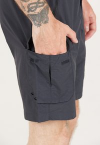 Mørkeblå shorts lavet af letvægtsstof, med en sidelomme med velcro og trykknaplukninger, samt en flat søm forneden.