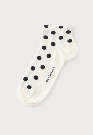 Calcetín blanco con lunares negros y el texto ""marimekko"", colocado extendido sobre un fondo liso y claro.
