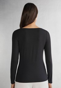 Schwarzes Langarmoberteil mit quadratischem Ausschnitt und glattem, elastischem Material. Hat eine enganliegende Silhouette und ein minimalistisches Design.