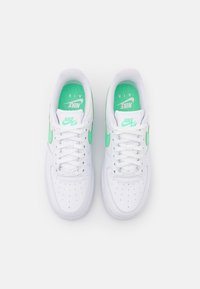 Valkoiset tennarit vihreillä yksityiskohdilla. Mallissa on sileä nahkapäällinen, rei'itetty varvasosa ja paksu kumipohja. Nauhat ja merkki kielen kohdalla.