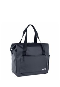 Borsa da viaggio in tessuto grigio con due spallacci, una tasca frontale con zip e una forma rettangolare. Presenta logo e dettagli testurizzati.