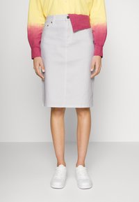 Vaaleanharmaa denim-hame, jossa on suora leikkaus, napitus edessä ja sivutaskut, yhdistettynä keltaiseen paitaan, jossa on vaaleanpunaiset liukuvärjätyt hihat.