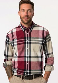 Camicia a scacchi con colori rosso, grigio, nero e beige. Presenta un colletto a bottoni, maniche lunghe e una tasca sul petto. Materiale in cotone.