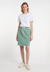 Randet blyantnederdel i grøn og hvid, med elastisk talje og snor. Samlet med en simpel hvid t-shirt med rund hals og sneakers.