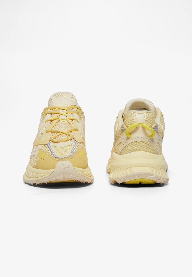 Paar gelbe Sneaker aus Mesh und Gummi, von vorne und hinten auf weißem Hintergrund gezeigt, wobei die Textur der Sohle und Details der Schnürsenkel hervorgehoben sind.