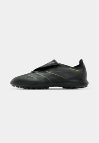 Black soccer cleat with green accents, featuring a textured upper, smooth lines, and studded outsole for traction. Includes a loose flap design.