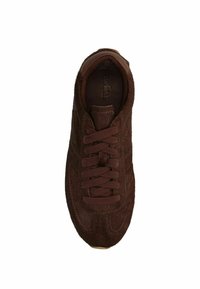 Brown suede sneaker with fabric laces, rounded toe, and textured surface. Features subtle stitching and a cushioned interior.