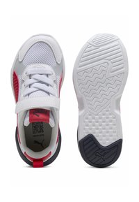 Baskets blanches avec des accents rouges et des panneaux en maille, dotées d'une sangle Velcro, d'une fermeture à lacets et d'une semelle en caoutchouc avec une adhérence texturée.