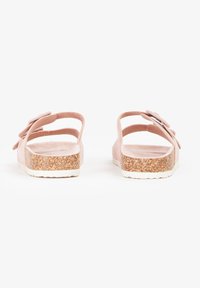 Lyserøde sandaler med flere tynde stropper og en tekstureret korksål. Blødt, nubuck-lignende materiale med en dekorativ blomsteraccent på siden.