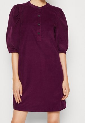 Lila corduroy jurk met opgeblazen mouwen tot aan de elleboog en een knoopsluithals aan de voorkant in het midden.