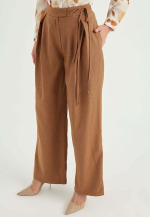 Bordeauxwijdte broek van zacht materiaal met een hoge taille en een strikriemdetail, aangevuld met puntige nude hakken.
