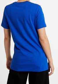 Blå bomullströja med rundad halsringning, korta ärmar, en avslappnad passform och en slät textur. Inga synliga mönster eller grafik.