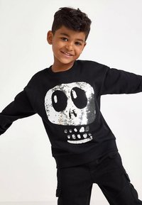 Sort sweatshirt med et pailletkranie i sølv, med rund halsudskæring og lange ærmer. Tekstureret stof med en glat finish.