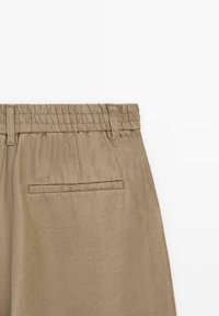 Khakihose aus strukturiertem Stoff mit elastischem Bund und Gesäßtasche. Das Design ist sauber und schlank, ohne zusätzliche Verzierungen.