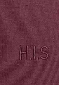 Strukturierter bordeauxfarbener Stoff mit gestickten Buchstaben "H.I.S." in einem kontrastierenden Farbton, der an der Unterseite zentriert ist. Weicher und dehnbarer Stoff.