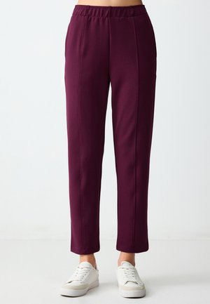 Pantaloni marroni a vita alta con gamba dritta, caratterizzati da una trama liscia e cuciture a contrasto. Abbinati a sneakers bianche.