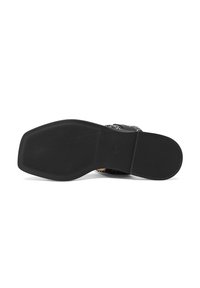 Suola di scarpa in gomma nera con un motivo di grip testurizzato, dotata di un logo inciso e bordi lisci, progettata per trazione e durata.