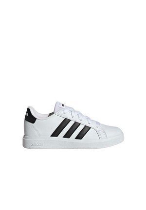 Witte Adidas lage sneaker met zwarte strepen, witte veters en een gestructureerde rubberen zool, gezien vanaf de buitenkant tegen een effen achtergrond.
