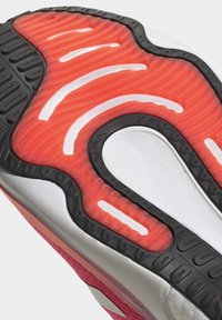 Suela de calzado deportivo con una banda de rodadura de goma negra, acolchado de un rojo brillante con textura ondulada y acentos blancos. Diseño distintivo para un mejor agarre.