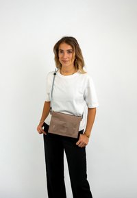 Borsa a tracolla marrone con tasca anteriore trasparente, tracolla blu regolabile, forma rettangolare e superficie liscia. Design minimalista.