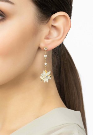 Gold-toned dangle earrings feature a floral design with crystal accents, highlighted by a three-tier structure and a shiny finish.