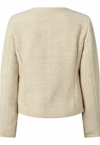 Veste beige à motif chevrons avec un col rond et des manches longues, fabriquée en tissu texturé, présentant une coupe courte et des coutures nettes.