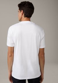 T-shirt bianco con maniche corte, collo rotondo e una texture di cotone liscia. Design semplice, senza motivi o loghi visibili.