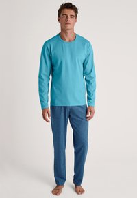 Lange mouwen turquoise shirt gecombineerd met blauwe pyjamabroek met een wit stippenpatroon; katoenen stof, relaxed fit, eenvoudig ontwerp.