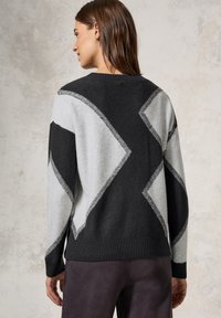 Pull en laine avec un motif géométrique noir et gris, doté d'un ourlet et de bords côtelés, mettant en avant une texture douce.