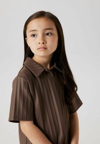 Brahno prugasto kratko polo majico z klasičnim ovratnikom in gladko teksturo. Majica ima vertikalne črte za dodatno podrobnost.