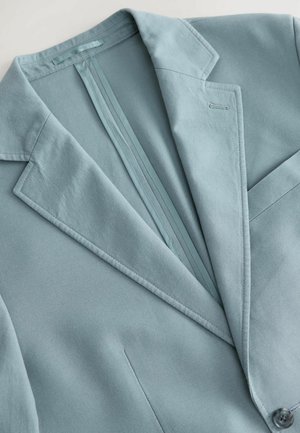 Lyseblå skræddersyet blazer med klapkrave, enkelt knaplukning og en subtil struktureret stof. Inkluderer en rygventil detalje.