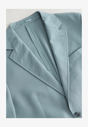 Ljusblå skräddarsydd blazer med notch-krage, enkel knappstängning och ett subtilt texturerat tyg. Inkluderar detalj med ryggslits.