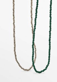Deux colliers de perles suspendus, l'un avec des perles facettées gris métallisé et l'autre avec des perles facettées vert foncé sur un fond blanc.