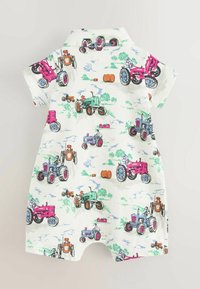 Robe courte à manches courtes en tissu crème avec des illustrations de tracteurs colorés en rose, vert et bleu, dotée d'un col pointu et d'une fermeture à pressions.