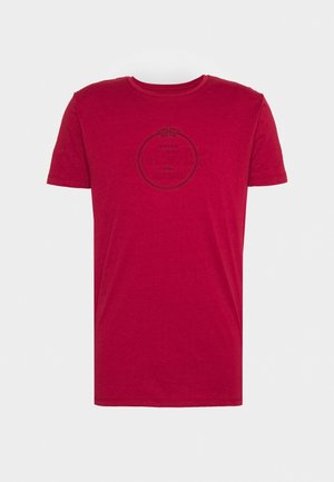 Rød bomuld T-shirt med rund halsudskæring og korte ærmer. Har et sort cirkulært logo på forsiden. Blød tekstur. Almindelig pasform.