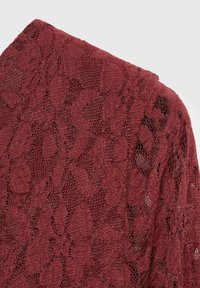Burgundy lace textile with floral pattern and open weave, featuring a textured surface and intricate design details.