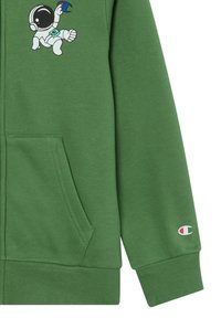 Felpa verde con zip in cotone, caratterizzata da una grafica di un astronauta cartone sul petto. Include tasche laterali e polsini a costine con dettagli del logo.