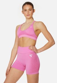 Roze sportoutfit met een fitte sportbh met een gestructureerde band en hoge shorts met een verlooppatroon, gemaakt van rekbaar materiaal.