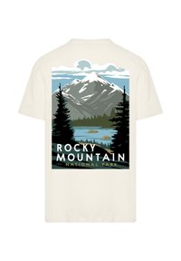 Cream-colored t-shirt featuring a graphic of Rocky Mountain National Park, depicting a mountain, lake, and trees in green and blue hues.