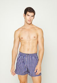 Boxershorts i blå, röd och vit rutmönster, med elastisk midja och en enda framknapp. Tillverkade av bomull.