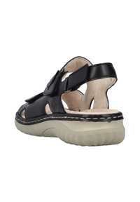 Sandale en cuir noir avec un design découpé, des lanières réglables et une semelle rembourrée de couleur claire. Présente un intérieur beige et des accents de couture.