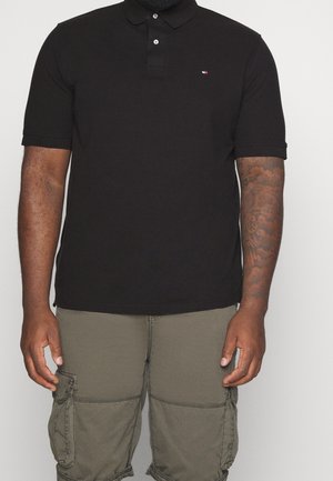 Zwarte polo-shirt met een kraag, twee knopen op de sluiting en een klein logo op de borst. Zacht materiaal, korte mouwen en een getailleerd ontwerp.