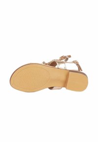 Sandal in oro metallico con suola in gomma marrone textured, caratterizzato da una forma curva, punta aperta e fasce decorative con un dettaglio a fiocco.