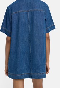 Krótka niebieska sukienka dżinsowa z krótkimi rękawami, z kontrastowymi szwami, luźnym krojem i prostym dołem.