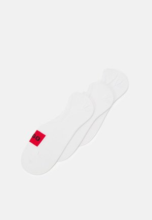 Trois paires de chaussettes blanches à coupe basse avec un accent rouge et du texte noir. Fabriquées en tissu doux avec des détails côtelés sur les bords.