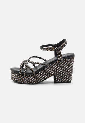 Sandale plateforme noire avec des brides croisées, motif texturé avec des carrés orange et blancs, bride à la cheville avec détail boucle, semelle en caoutchouc.