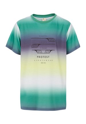 Ung person stående iført T-shirt med grøn, gul og lilla gradient og tekst, beige shorts, hvide sokker med sorte striber og sorte sneakers.