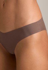Lenjerie de baie bikini maro, fără cusături, cu textură netedă, design minimalist și talie joasă, evidențiind o parte din corp.